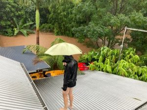 person standing on tin roof with flood waters around the home